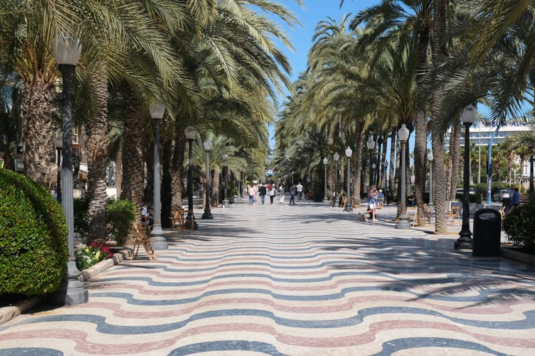 Alicante's palm-lined Explanada promenade, its wave-patterned marble pavement running toward the marina.