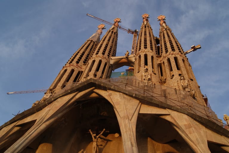 The Passion façade towers of the Sagrada Família rising against a blue sky in warm afternoon light.