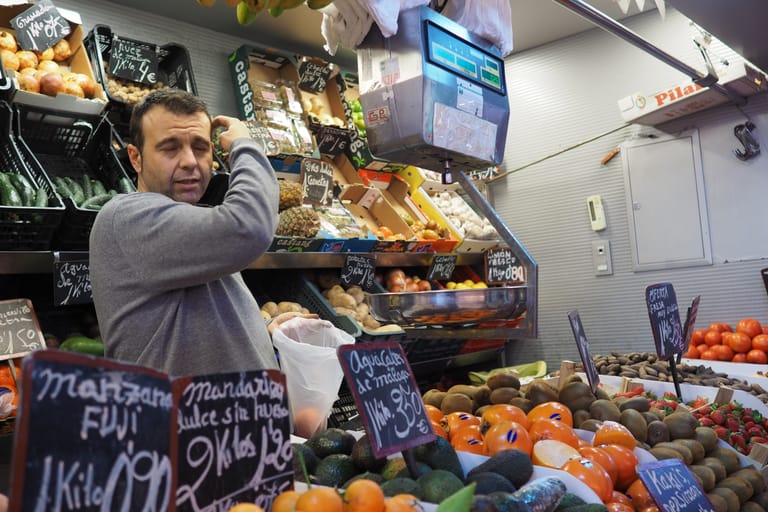 A greengrocer's stall inside Málaga's Mercado Central de Atarazanas, its produce priced by the kilo on chalked boards.