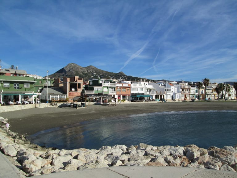 The low, brightly painted houses of Pedregalejo along Málaga's eastern seafront, with the Montes de Málaga rising behind them.