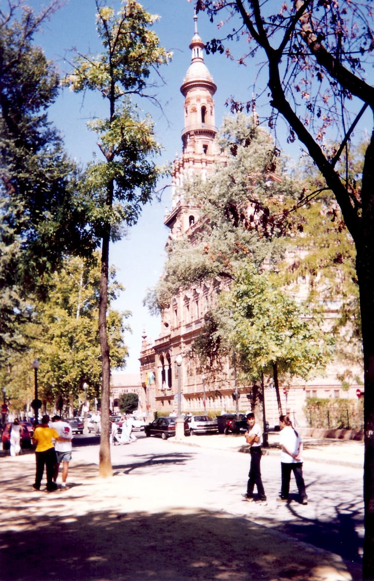 A shaded tiled walkway among the palms and clipped hedges of Seville's Parque de María Luisa.