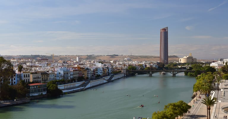 The Guadalquivir river curving past Seville's riverside promenade, seen from the Torre del Oro.