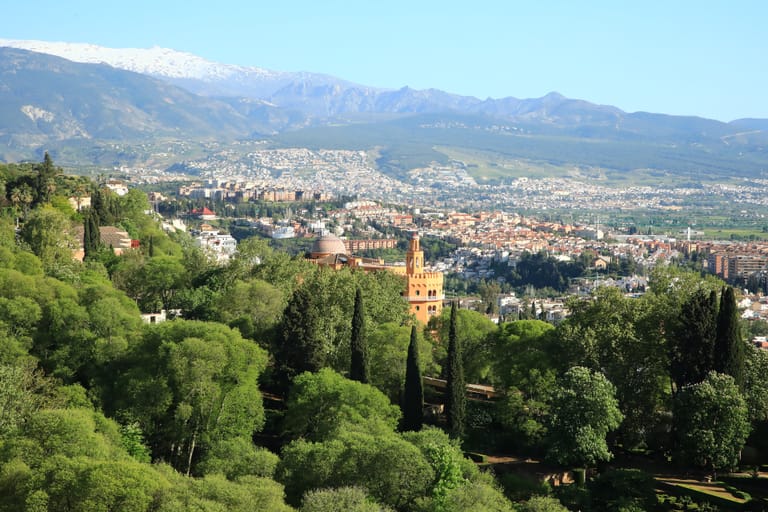 Granada spread below the Alhambra's gardens, with the snow-capped Sierra Nevada rising behind the city.