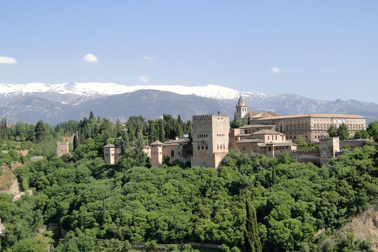 The Alhambra on its ridge above Granada with the snow-topped peaks of the Sierra Nevada rising behind it.
