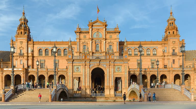 The brick and tiled arcades of Seville's Plaza de España in late afternoon sun.
