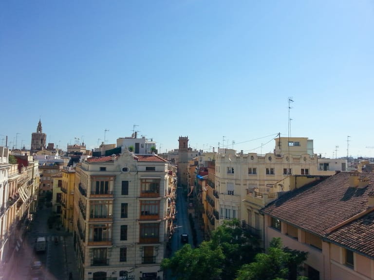 A view across the terracotta-tiled rooftops and bell towers of Valencia's historic old town under a clear sky.